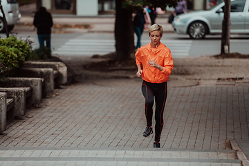 Image showing A blonde in a sports outfit is running around the city in an urban environment. The hot blonde maintains a healthy lifestyle.