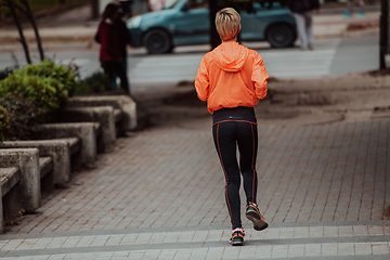 Image showing A blonde in a sports outfit is running around the city in an urban environment. The hot blonde maintains a healthy lifestyle.