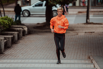 Image showing A blonde in a sports outfit is running around the city in an urban environment. The hot blonde maintains a healthy lifestyle.