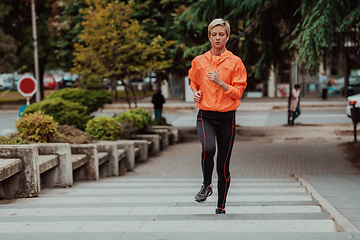 Image showing A blonde in a sports outfit is running around the city in an urban environment. The hot blonde maintains a healthy lifestyle.