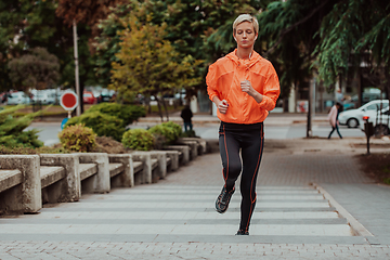 Image showing A blonde in a sports outfit is running around the city in an urban environment. The hot blonde maintains a healthy lifestyle.