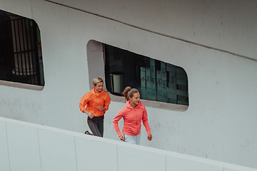 Image showing Two women in sports clothes running in a modern urban environment. The concept of a sporty and healthy lifestyle