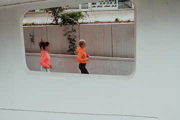 Image showing Two women in sports clothes running in a modern urban environment. The concept of a sporty and healthy lifestyle