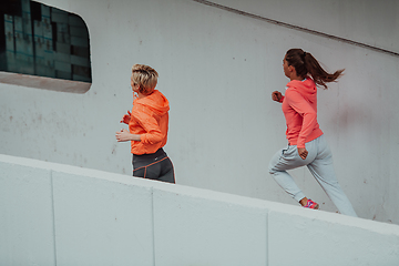 Image showing Two women in sports clothes running in a modern urban environment. The concept of a sporty and healthy lifestyle