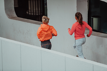 Image showing Two women in sports clothes running in a modern urban environment. The concept of a sporty and healthy lifestyle