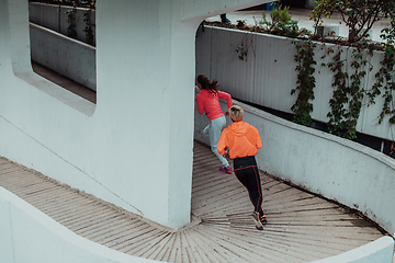 Image showing Two women in sports clothes running in a modern urban environment. The concept of a sporty and healthy lifestyle