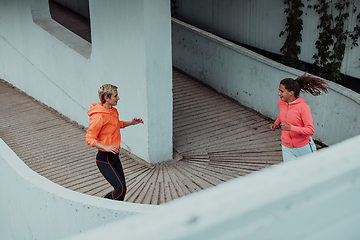 Image showing Two women in sports clothes running in a modern urban environment. The concept of a sporty and healthy lifestyle