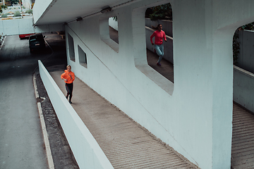 Image showing Two women in sports clothes running in a modern urban environment. The concept of a sporty and healthy lifestyle