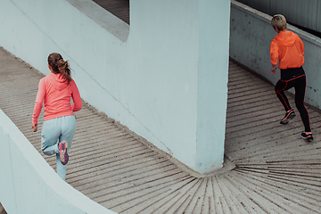 Image showing Two women in sports clothes running in a modern urban environment. The concept of a sporty and healthy lifestyle