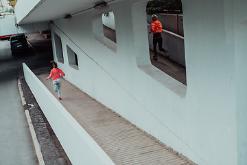 Image showing Two women in sports clothes running in a modern urban environment. The concept of a sporty and healthy lifestyle