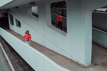 Image showing Two women in sports clothes running in a modern urban environment. The concept of a sporty and healthy lifestyle