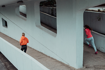 Image showing Two women in sports clothes running in a modern urban environment. The concept of a sporty and healthy lifestyle