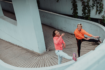 Image showing Two women warming up together and preparing for a morning run in an urban environment. Selective focus