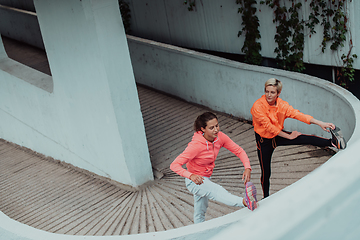 Image showing Two women warming up together and preparing for a morning run in an urban environment. Selective focus