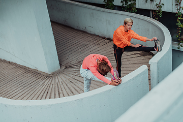 Image showing Two women warming up together and preparing for a morning run in an urban environment. Selective focus