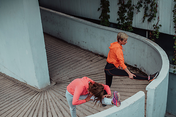 Image showing Two women warming up together and preparing for a morning run in an urban environment. Selective focus