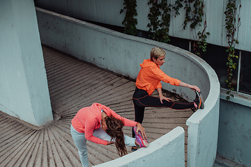 Image showing Two women warming up together and preparing for a morning run in an urban environment. Selective focus