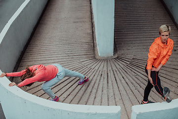 Image showing Two women warming up together and preparing for a morning run in an urban environment. Selective focus