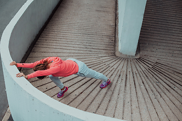 Image showing Fit attractive woman in sportswear stretching before jogging. Workout, sport, activity, fitness, vacation and training concept.