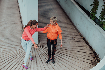 Image showing Two women warming up together and preparing for a morning run in an urban environment. Selective focus