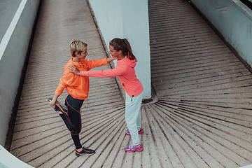 Image showing Two women warming up together and preparing for a morning run in an urban environment. Selective focus