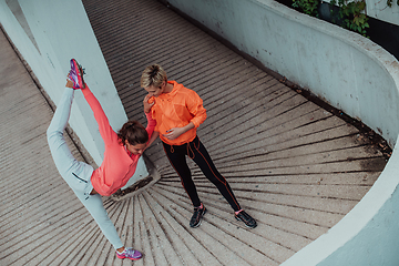 Image showing Two women warming up together and preparing for a morning run in an urban environment. Selective focus