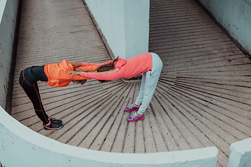 Image showing Two women warming up together and preparing for a morning run in an urban environment. Selective focus