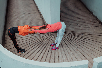 Image showing Two women warming up together and preparing for a morning run in an urban environment. Selective focus