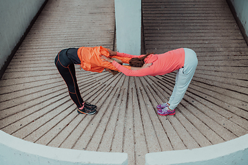 Image showing Two women warming up together and preparing for a morning run in an urban environment. Selective focus