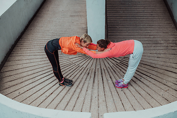 Image showing Two women warming up together and preparing for a morning run in an urban environment. Selective focus