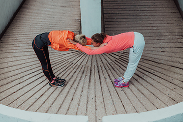 Image showing Two women warming up together and preparing for a morning run in an urban environment. Selective focus