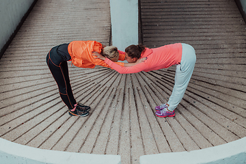 Image showing Two women warming up together and preparing for a morning run in an urban environment. Selective focus