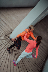 Image showing Two women warming up together and preparing for a morning run in an urban environment. Selective focus