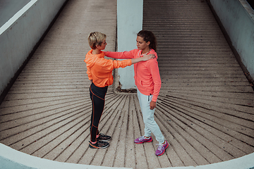 Image showing Two women warming up together and preparing for a morning run in an urban environment. Selective focus