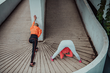 Image showing Two women warming up together and preparing for a morning run in an urban environment. Selective focus