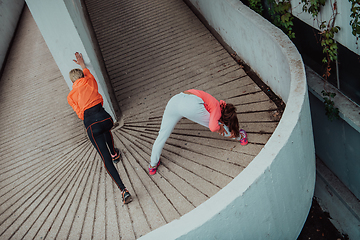 Image showing Two women warming up together and preparing for a morning run in an urban environment. Selective focus