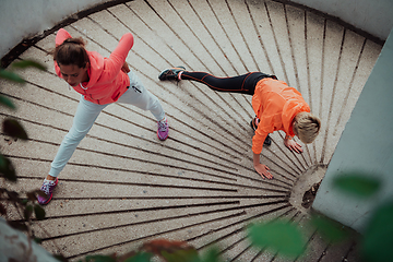 Image showing Two women warming up together and preparing for a morning run in an urban environment. Selective focus