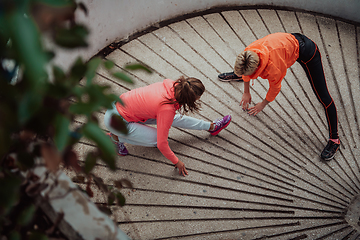 Image showing Two women warming up together and preparing for a morning run in an urban environment. Selective focus