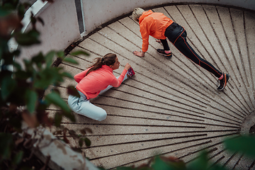 Image showing Two women warming up together and preparing for a morning run in an urban environment. Selective focus