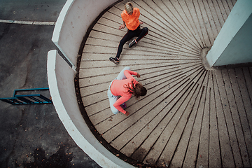 Image showing Two women warming up together and preparing for a morning run in an urban environment. Selective focus