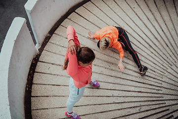 Image showing Two women warming up together and preparing for a morning run in an urban environment. Selective focus