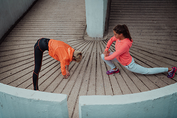 Image showing Two women warming up together and preparing for a morning run in an urban environment. Selective focus