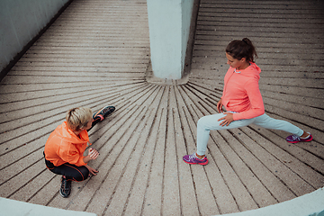 Image showing Two women warming up together and preparing for a morning run in an urban environment. Selective focus