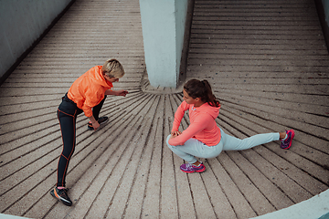 Image showing Two women warming up together and preparing for a morning run in an urban environment. Selective focus