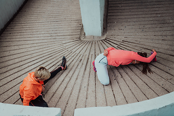 Image showing Two women warming up together and preparing for a morning run in an urban environment. Selective focus