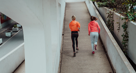 Image showing Two women in sports clothes running in a modern urban environment. The concept of a sporty and healthy lifestyle