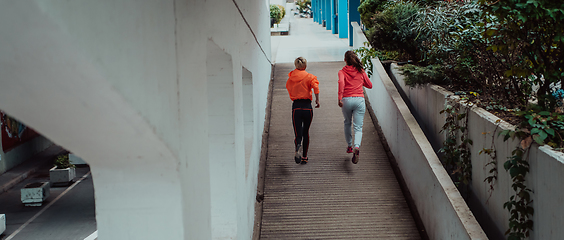 Image showing Two women in sports clothes running in a modern urban environment. The concept of a sporty and healthy lifestyle