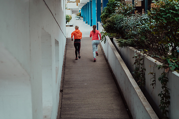 Image showing Two women in sports clothes running in a modern urban environment. The concept of a sporty and healthy lifestyle