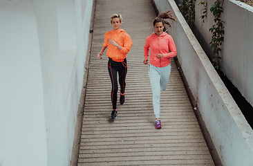 Image showing Two women in sports clothes running in a modern urban environment. The concept of a sporty and healthy lifestyle