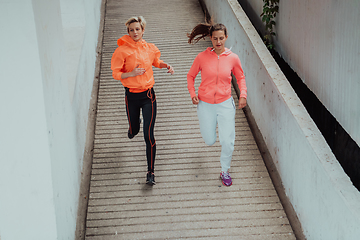 Image showing Two women in sports clothes running in a modern urban environment. The concept of a sporty and healthy lifestyle